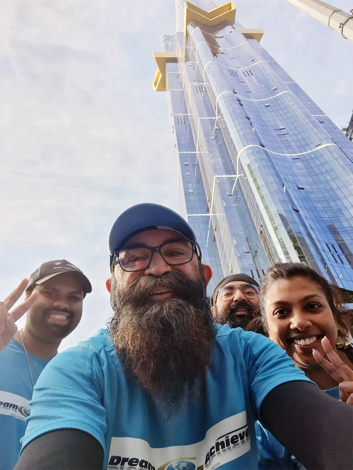 AVP Perminderjit Singh with three members of DreamAchiever Team posing for a selfie in front of the Australia 108 tower  