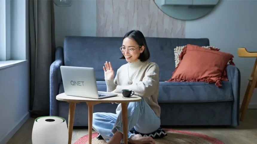 Girl who is doing QNET Part-Time talks to a business prospect on her laptop; she is wearing an Amezcua Chi Pendant and her home is equipped with HomePure Zayn