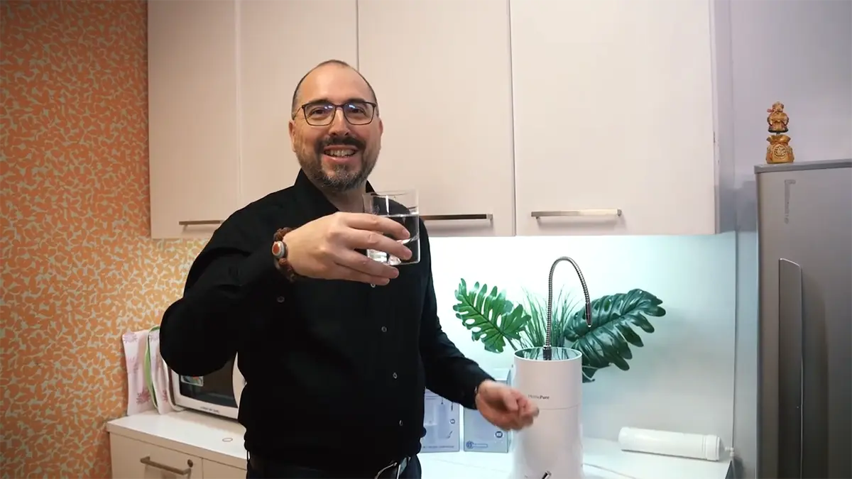 QI Director of International Operations JR Mayer holding up a glass of HomePure water at a QNET office 